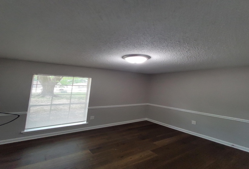 Room featuring wood-finish flooring, a window with blinds, and a flush-mount ceiling light fixture