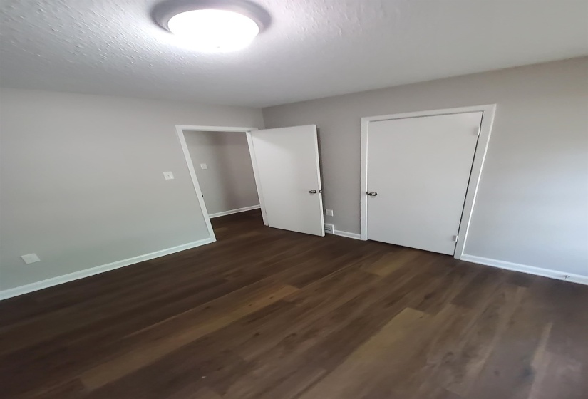 Interior room featuring wood-finish flooring, light gray walls, white trim, and a flush mount ceiling light