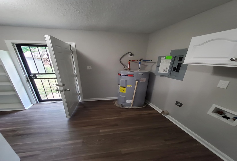Laundry area featuring wood-finish flooring, white wall cabinetry, and neutral wall paint