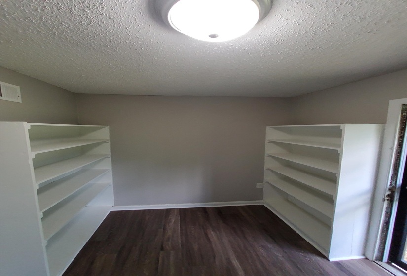 Room featuring two white built-in shelving units, wood-finish flooring, and neutral wall tones