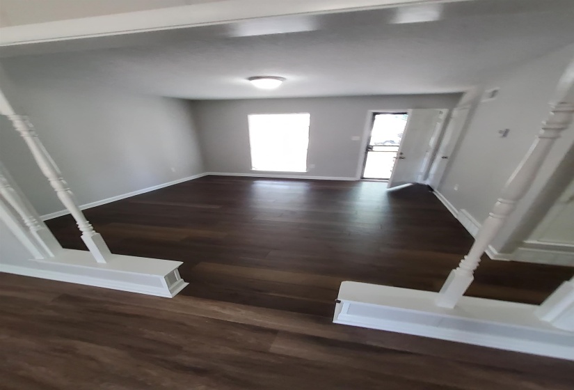 Spacious room featuring rich wood-finish flooring and light gray painted walls