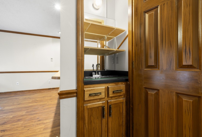 Built-in wet bar featuring a dark countertop, stainless steel sink, and wood-finish cabinetry