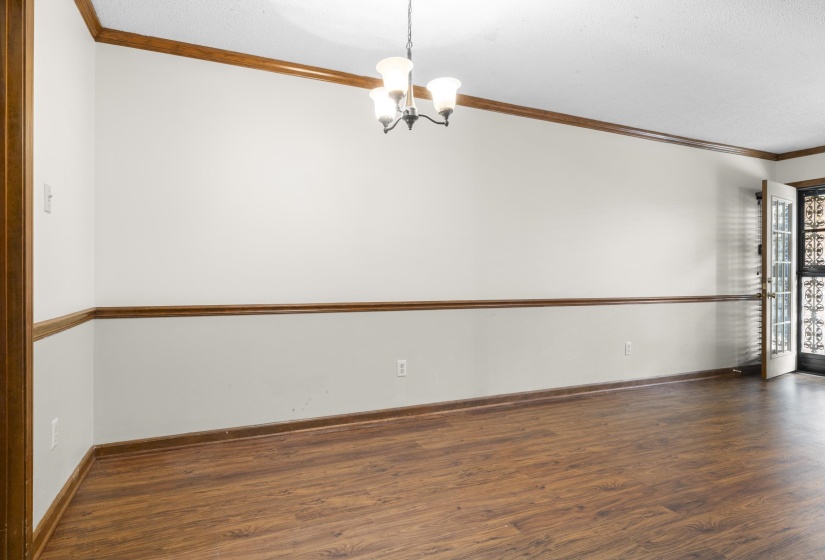 Spacious room featuring wood-finish flooring, two-tone wall paint, a decorative chair rail, and crown molding
