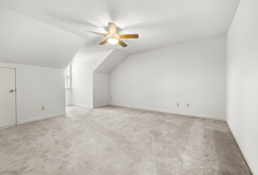 Carpeted room featuring a ceiling fan with integrated lighting, white walls, and a window providing natural light