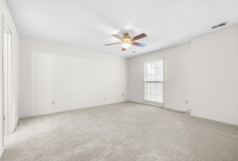 Spacious room featuring light-colored carpeting and a ceiling fan with integrated lighting
