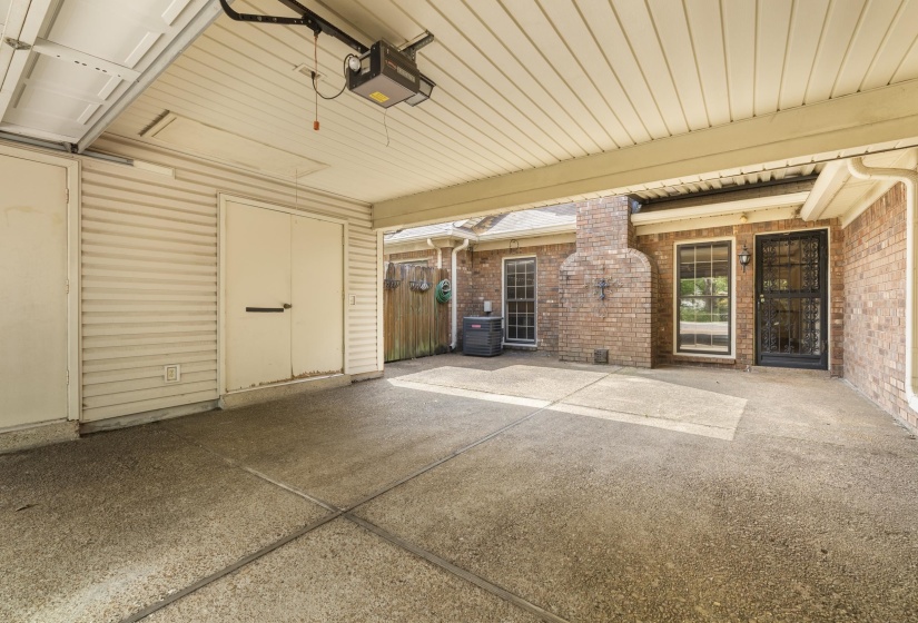 Carport featuring a concrete slab, brick exterior, and an attached storage room with double doors