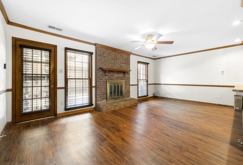 Living area featuring wood-finish flooring, a brick fireplace with a wood mantel, and a ceiling fan