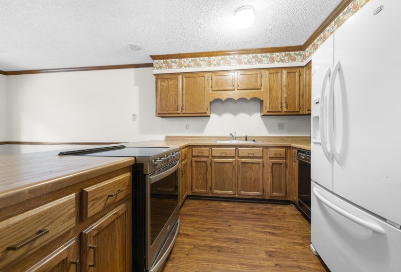 Kitchen featuring wood-finish flooring, oak cabinetry, and light-toned countertops