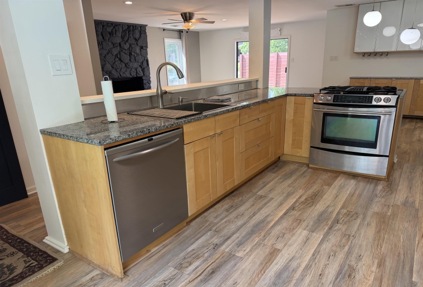 Kitchen featuring wood-finish flooring, light wood cabinetry, granite countertops, a stainless steel range, and a stainless steel dishwasher