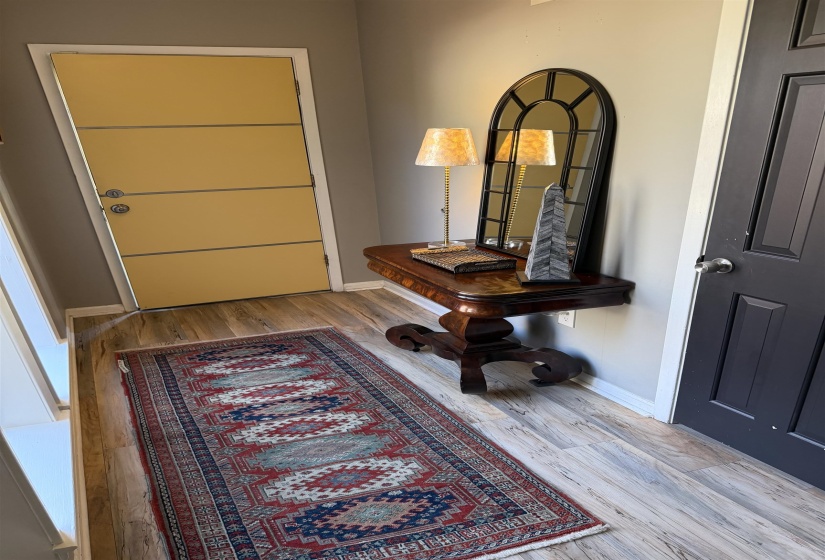 Light wood-finish flooring with a decorative entry table featuring a dark wood finish