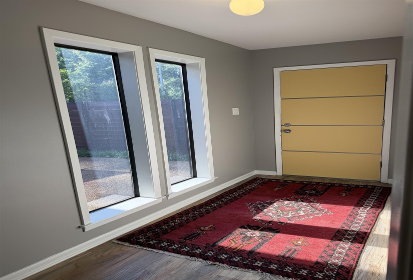 Entryway with wood-finish flooring, two vertical windows, and a modern paneled door