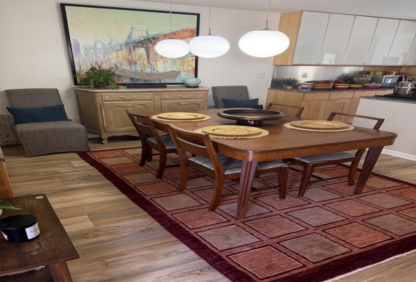 Dining area featuring pendant lighting, wood-finish flooring, a built-in kitchen countertop, and a stainless steel backsplash