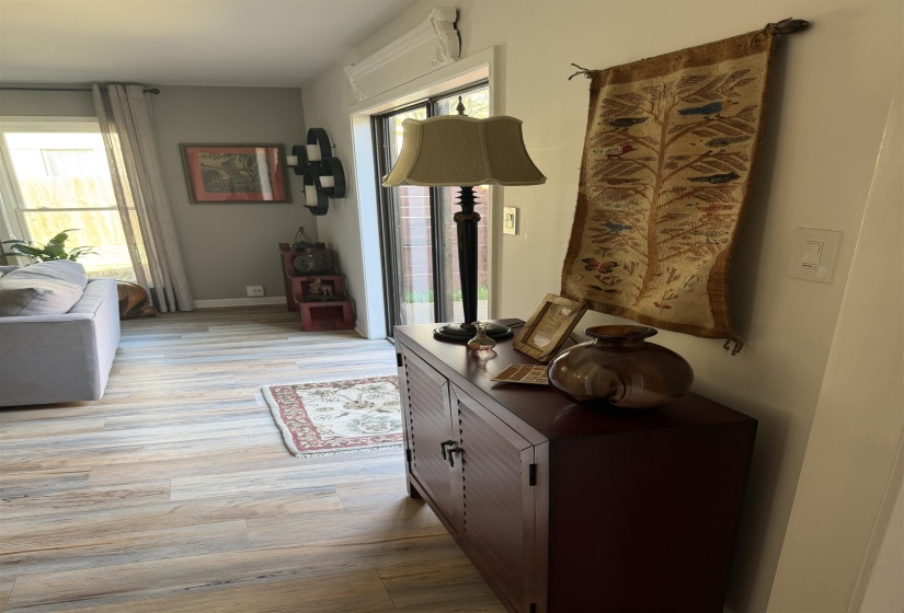Interior living space featuring wood-finish flooring, a wall-mounted air conditioning unit, and a sliding glass door with a transom window