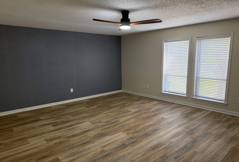 Spacious room featuring wood-finish flooring and a contemporary ceiling fan