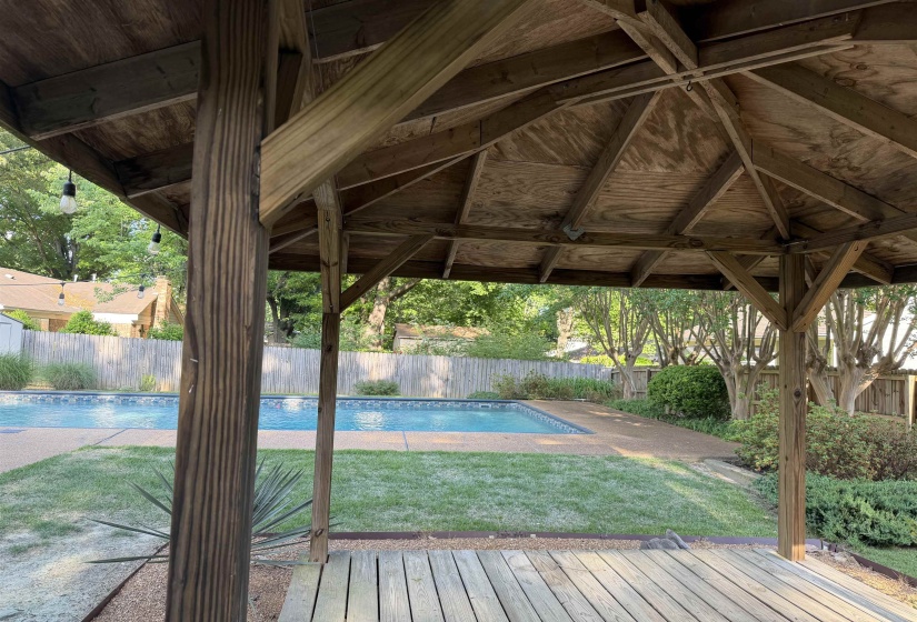 Wooden gazebo with slatted flooring provides a shaded outdoor space