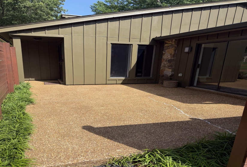 Exterior entry featuring board and batten siding, exposed aggregate patio, and stone veneer accents