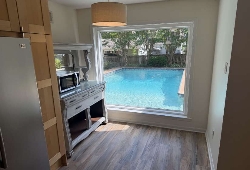 Expansive window overlooking a private swimming pool with a surrounding patio