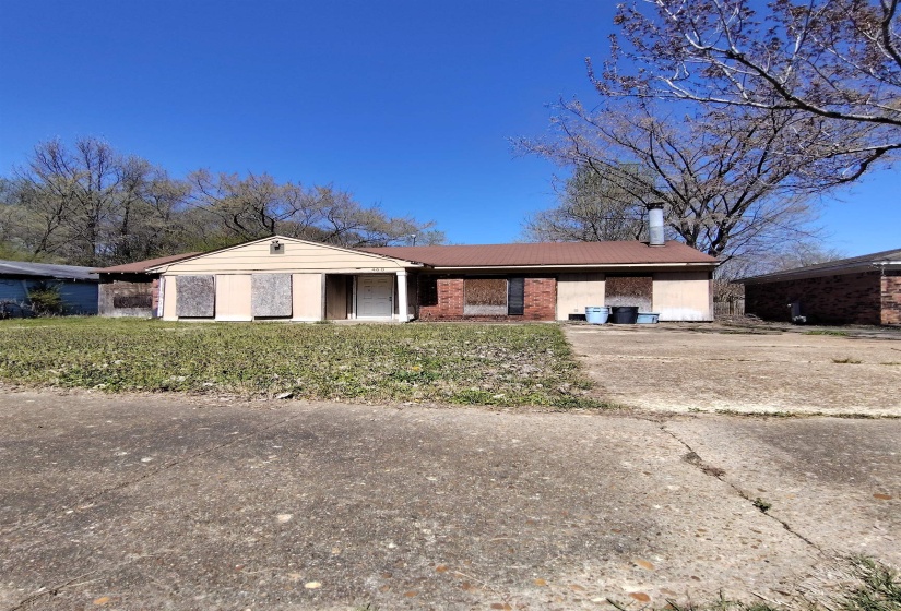 Single story home with brick siding, a chimney, concrete driveway, a front lawn, and an attached carport