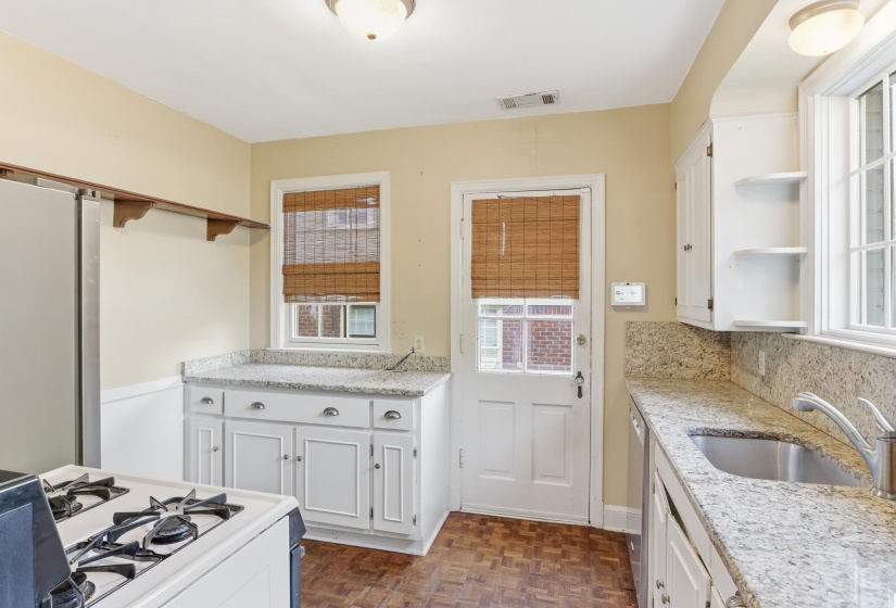 Kitchen featuring white cabinetry with brushed nickel hardware, granite-style countertops, mosaic tile-patterned flooring, and a stainless steel sink
