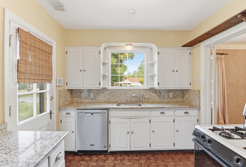 Kitchen featuring white cabinetry, light-toned countertops with matching backsplash, and wood-finish flooring
