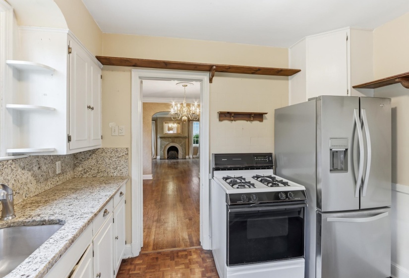 Functional kitchen featuring white cabinetry, granite countertops, a stainless steel refrigerator, and a gas range