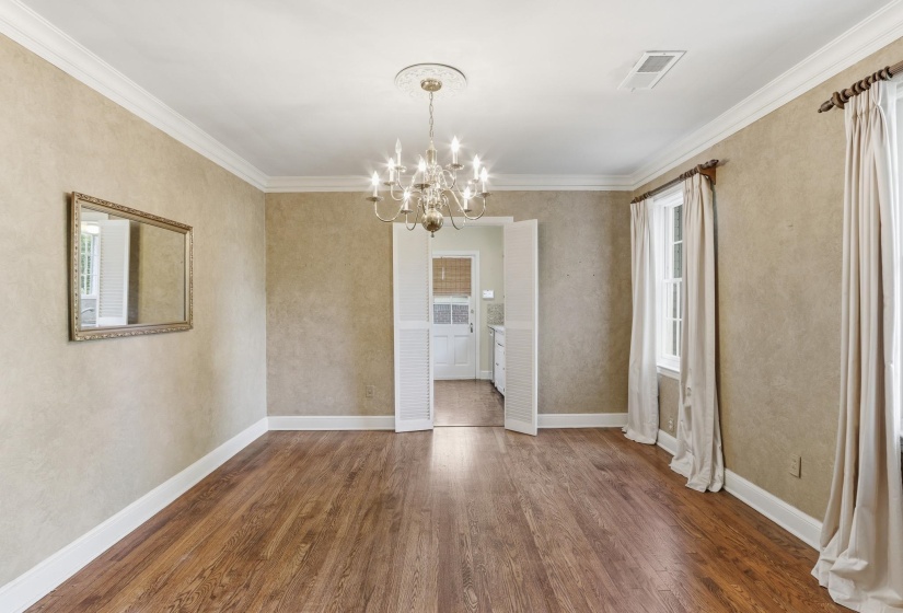 Spacious room featuring wood-finish flooring, two windows with drapery, and crown molding