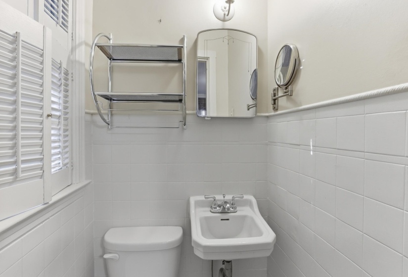Pedestal sink with chrome fixtures and white tiled wainscoting