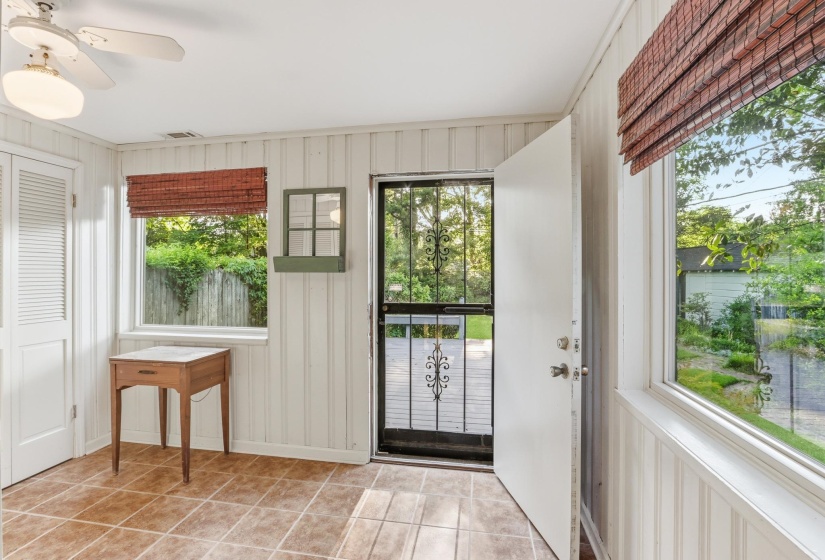 Entry area featuring tile flooring, vertical plank wall paneling, a ceiling fan with integrated lighting, and multiple windows with woven blinds