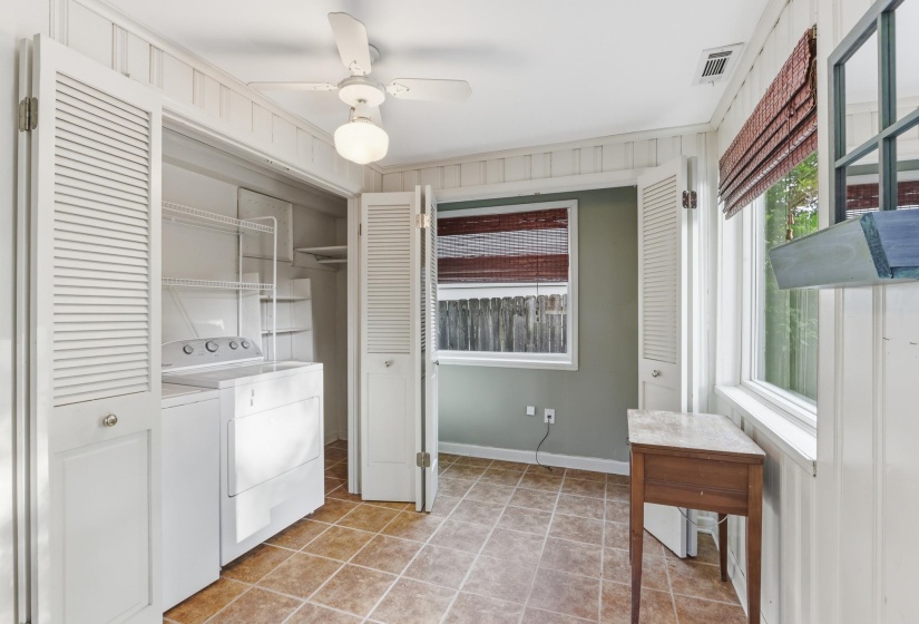 Utility room featuring tile flooring, beadboard wall paneling, a ceiling fan with light fixture, and a built-in laundry closet with louvered bifold doors
