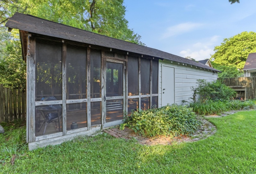 Detached accessory building featuring a screened porch entry, wood paneling, an asphalt shingle roof, and a side access door
