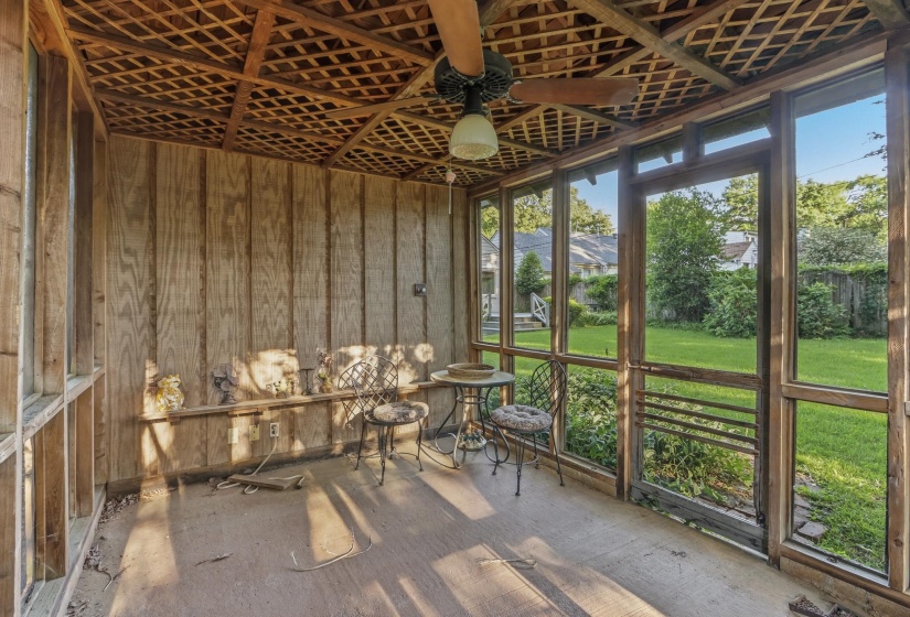 Screened porch featuring a lattice wood ceiling, wood-paneled walls, a ceiling fan with light fixture, and multiple large windows overlooking a green lawn