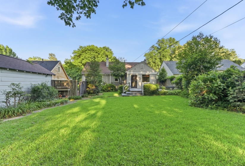 Expansive backyard featuring a lush lawn, mature perimeter landscaping, and a fenced boundary