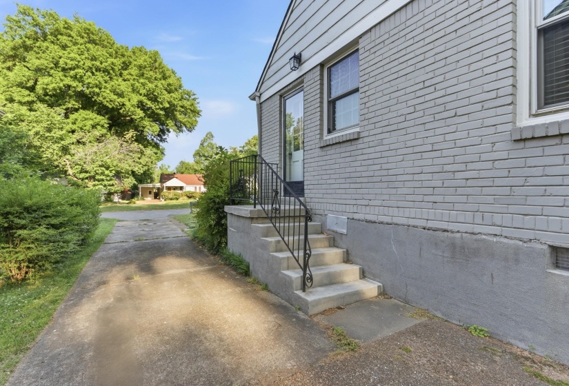 Concrete steps with wrought iron railing leading to a side entry door