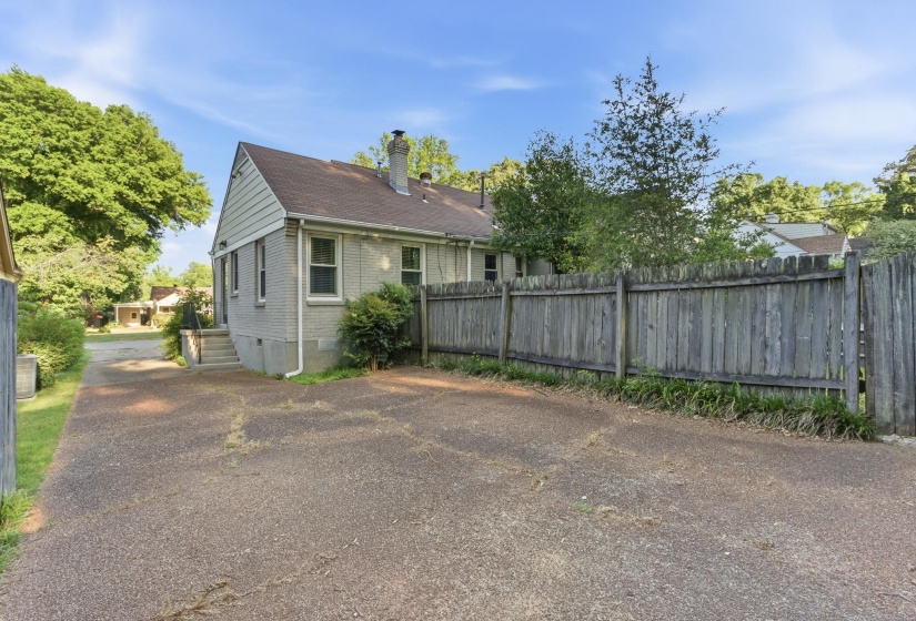 Property exterior featuring brick siding, a gabled roof, and a private wood fence
