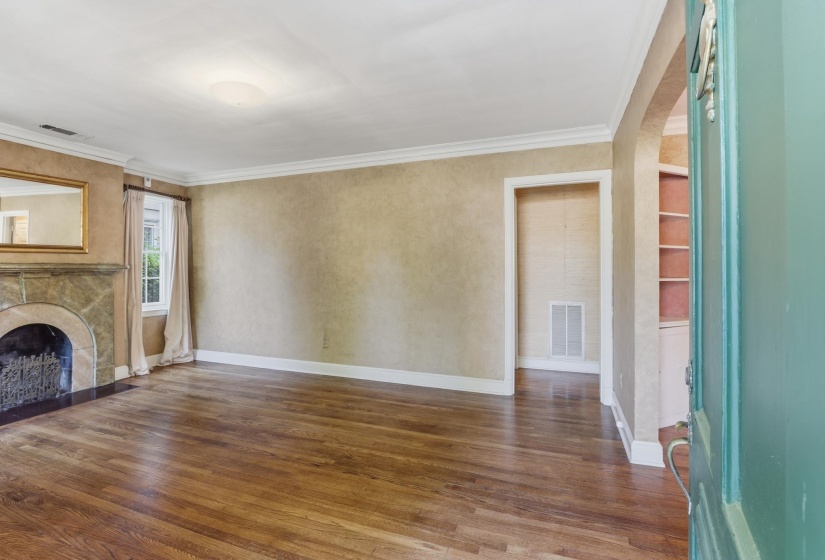 Spacious interior featuring wood-finish flooring, crown molding, and a stone-clad fireplace with a dark hearth