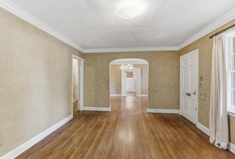 Spacious interior featuring wood-finish flooring, an arched doorway, and a multi-panel entry door
