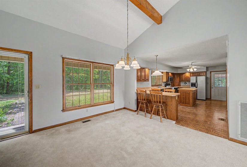 Vaulted ceiling with exposed wood beam and a chandelier over carpeted flooring