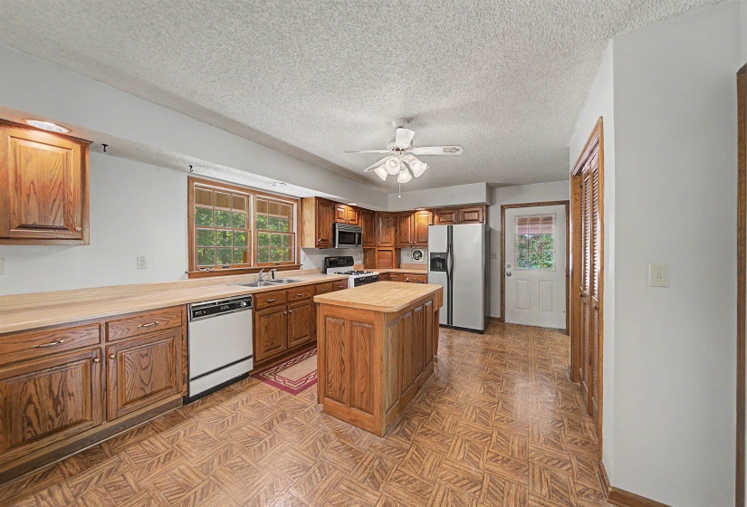 Kitchen featuring wood-finish cabinetry, a central island with countertop, and wood-finish flooring
