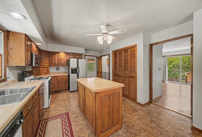 Kitchen featuring wood cabinetry, a center island with a wood-finish countertop, stainless steel appliances, and a gas range