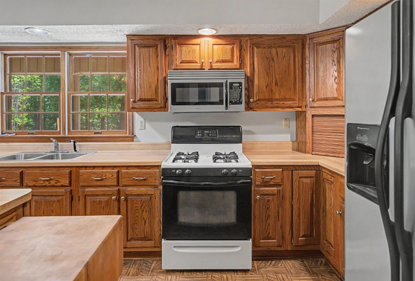 Kitchen with wood cabinetry, light countertops, and a stainless steel over-the-range microwave