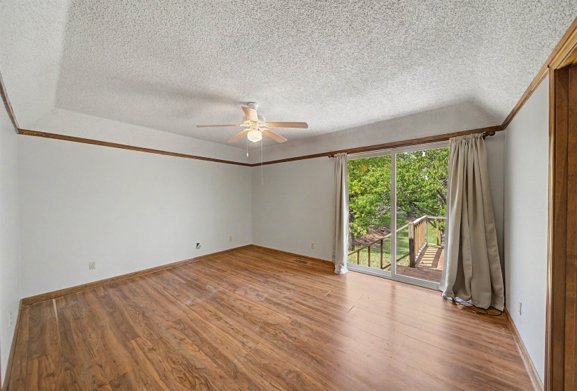 Spacious room featuring wood-finish flooring, white walls with wood trim, and a tray ceiling