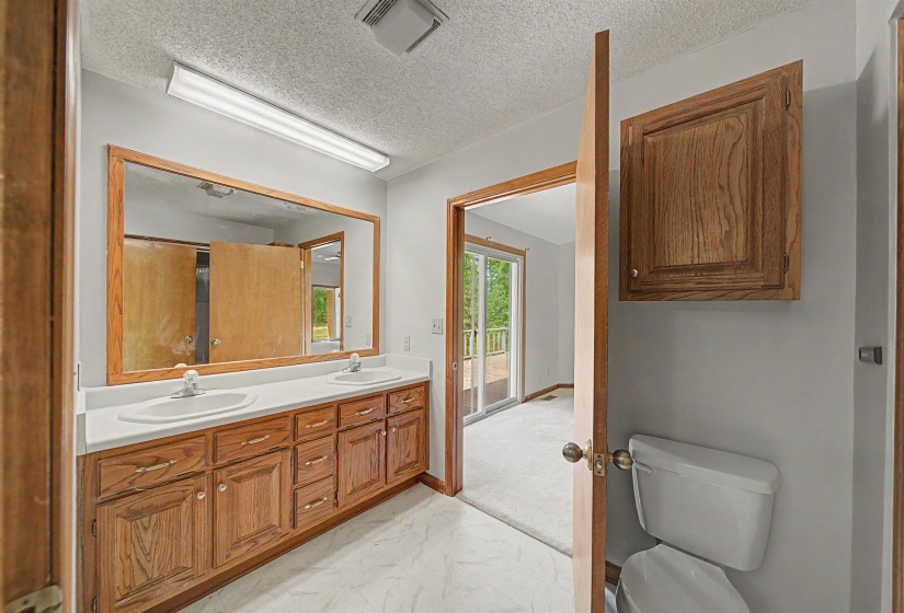 Bathroom featuring a dual vanity with oak cabinetry, white countertops, and a large wall-mounted mirror