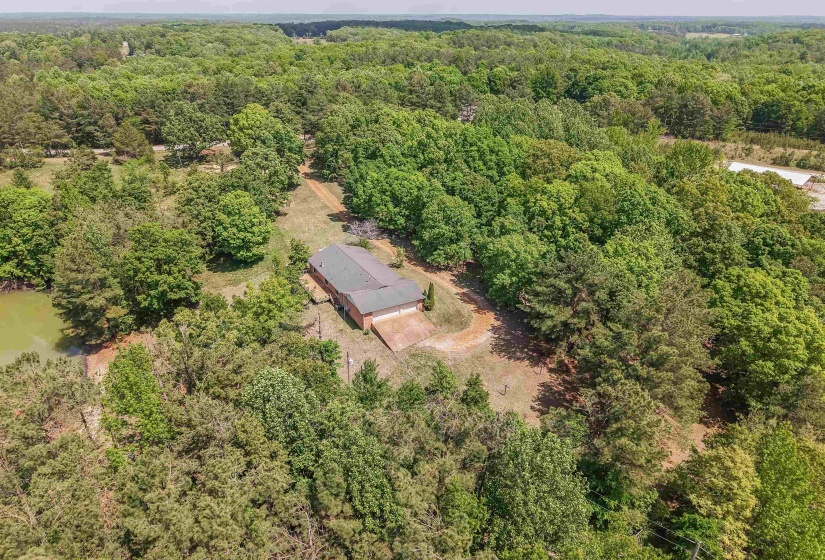 Expansive wooded acreage featuring a brick-sided residence with an attached garage and a private pond