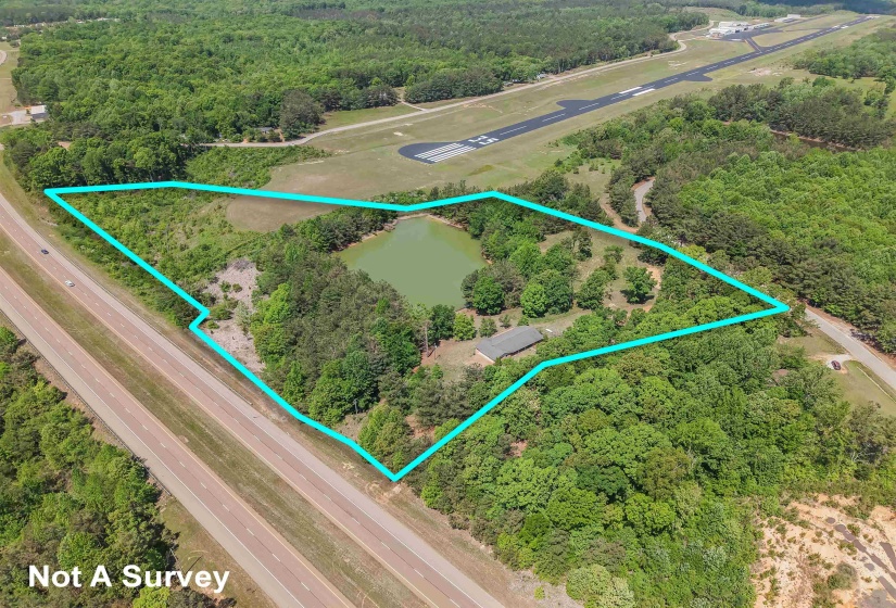 Expansive land parcel featuring a private pond and a single-story structure with a dark roof