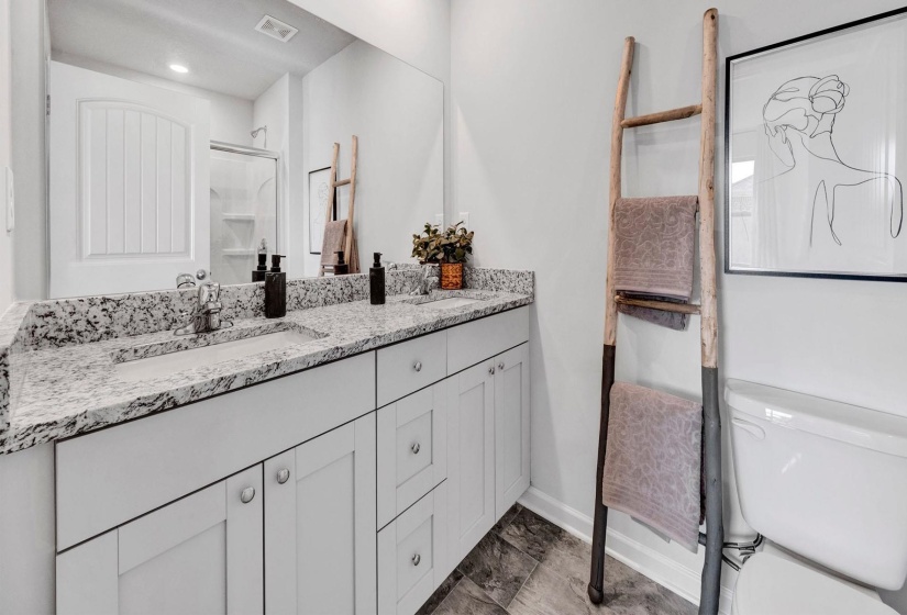 Full bathroom with double vanity and a shower stall