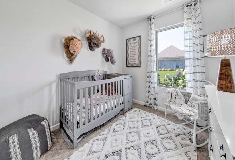 Bedroom featuring light colored carpet and a crib