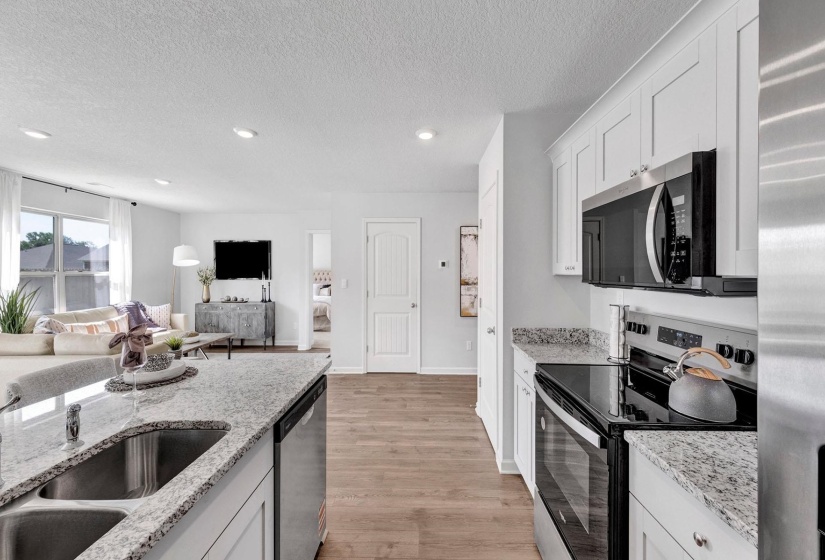 Kitchen featuring stainless steel appliances, white cabinetry, a textured ceiling, light stone counters, and light wood-style floors