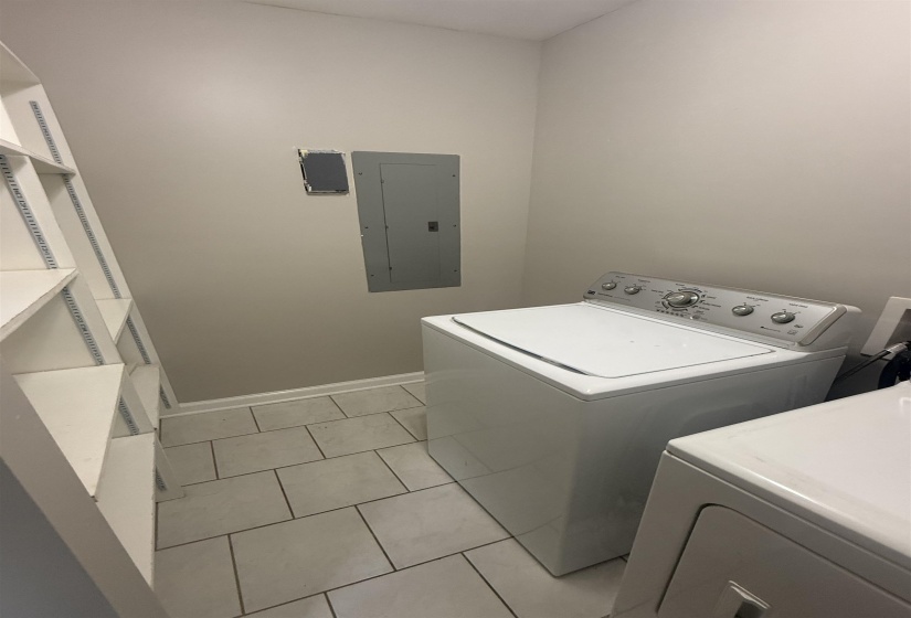 Laundry area featuring built-in shelving, light gray wall paint, and gray tile flooring