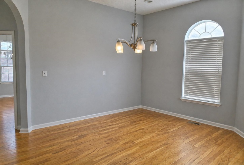 Room with wood-finish flooring, vaulted ceiling, and an arched window featuring interior blinds