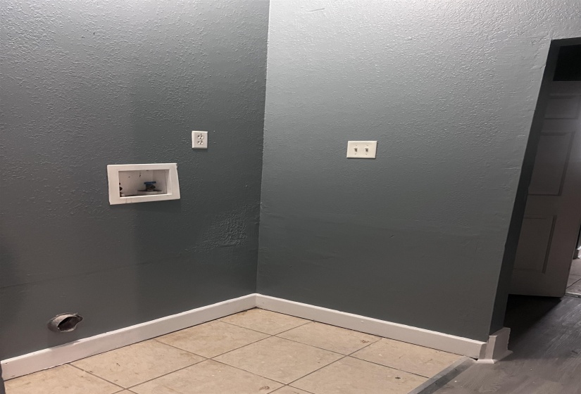 Utility area featuring textured walls, tile flooring, and white baseboards